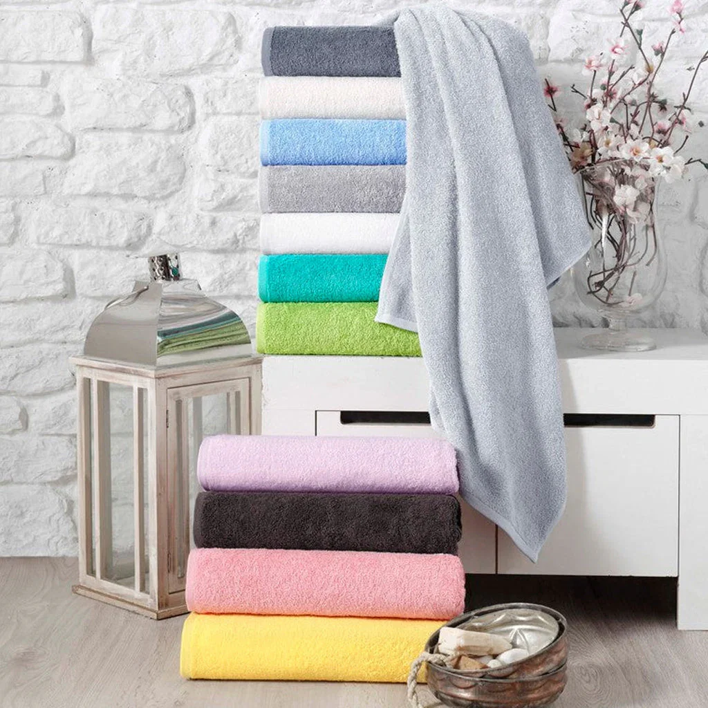 Colorful stack of folded Turkish towels displayed against a white brick wall with decorative elements.
