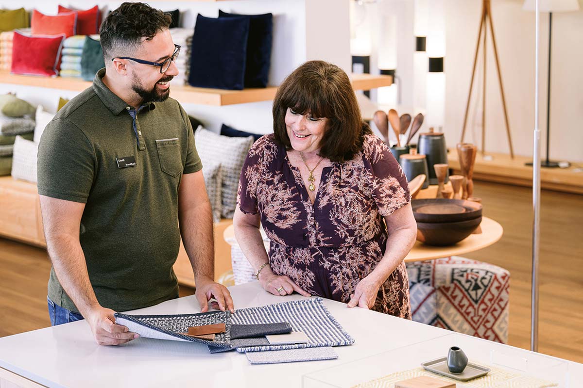 Customer and design associate looking at fabric and leather swatches.