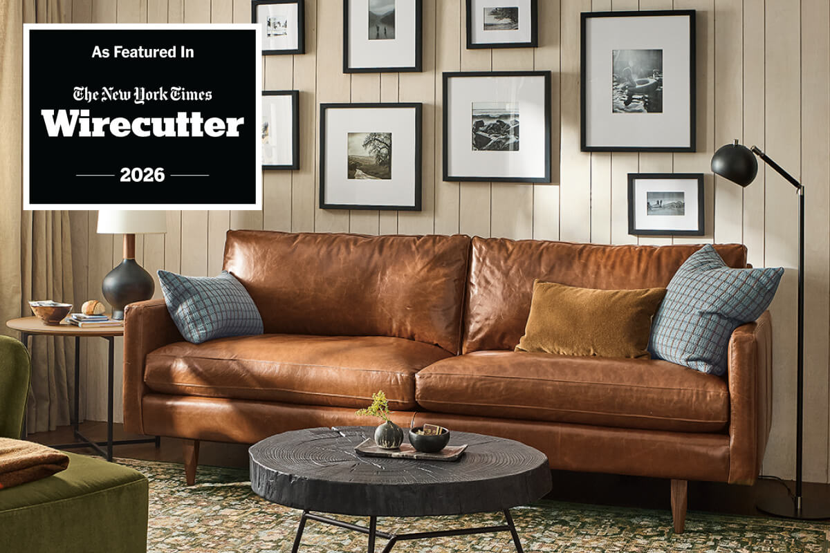 Jasper sofa in brown leather paired with patterned pillows, round coffee table and patterned area rug.