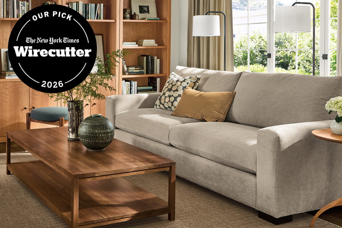 Metro sofa with light grey upholstery, patterned pillows and walnut coffee table in front of built-in shelving.