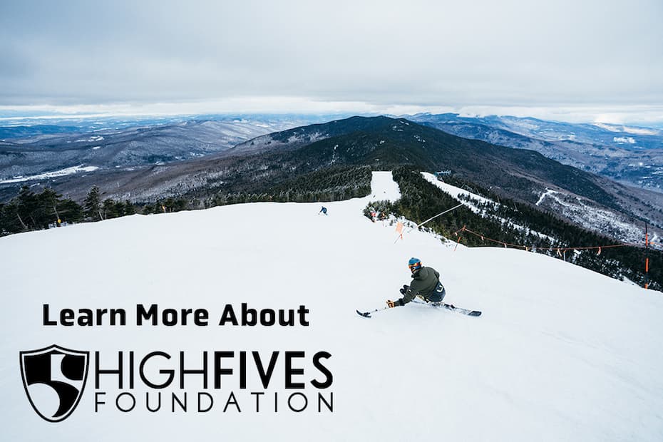 Mountain scene with athletes using adaptive equipment skiing down during a High Fives hosted program