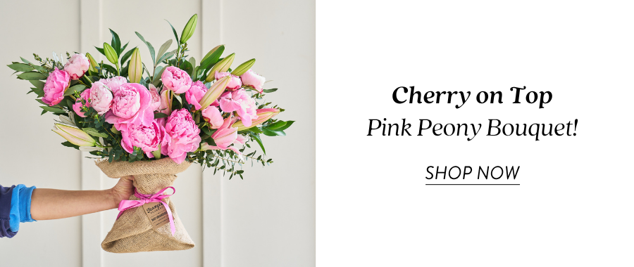 Product feature for “Cherry on Top Pink Peony Bouquet,” showing a burlap-wrapped bouquet with bright pink peonies, pale pink lilies, and greenery held out by someone in a blue sleeve, with a “Shop Now” link.