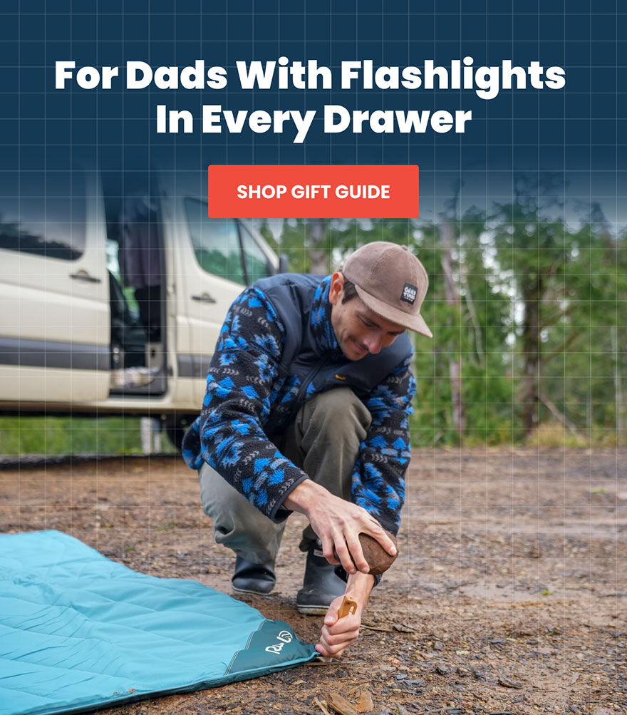 Dad secures a Rumpl Overland Mat on wet ground with tent stakes
