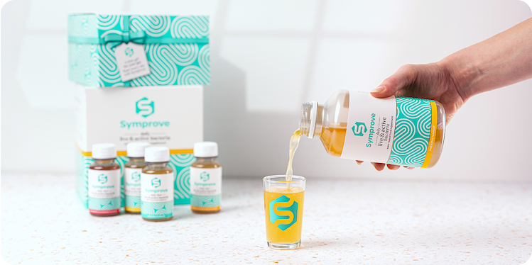 Symprove being poured into a shot glass with free gifts in the background