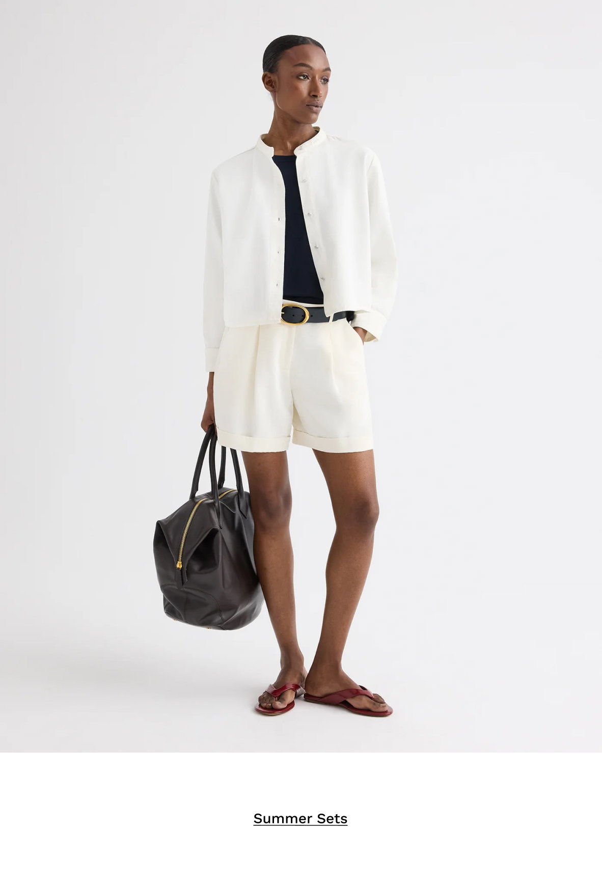 Image of a model in a white shirt, white shorts and a black bag with text beneath.