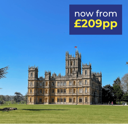 A grand historic building with a clear blue sky in the background, set in a green landscape.