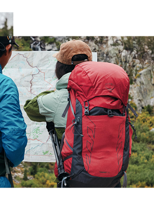 A man and woman consult a map. The woman wears Osprey Tempest 33L Rucksack on her back. 