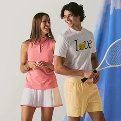 Ein lächelnder Mann und eine Frau in Tenniskleidung stehen vor einem blauen Stoffhintergrund, wobei der Mann einen Tennisschläger hält.