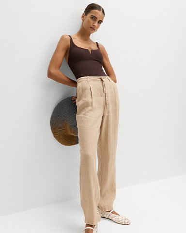Woman wearing Sandstone Pure Linen Pleat Front Belted Tapered Trousers and Peat U-Notch Textured Bandeau Swimsuit