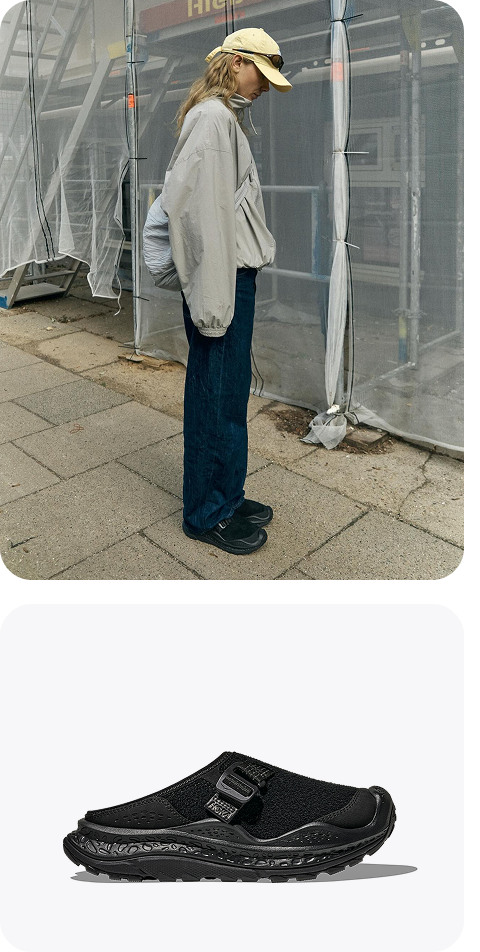 Person standing on a city sidewalk under scaffolding, wearing Ora Primo EXT model. Ora Primo EXT in Black / Black