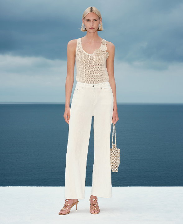 Woman wearing a Light Cream Cotton Blend Crochet-Style Knitted Vest and Soft White Cotton Rich Textured Straight Leg Trousers