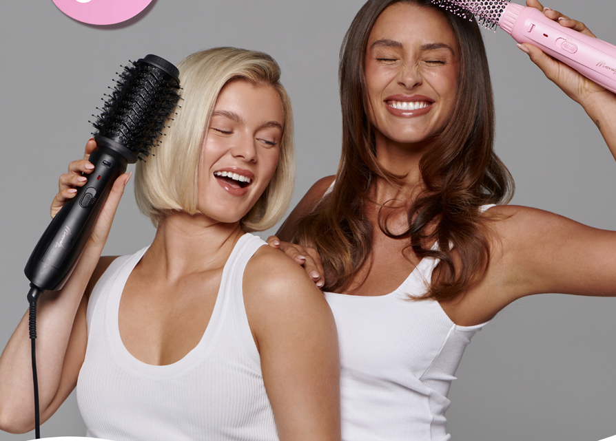 Two women holding mermade hair blow dry brushes 