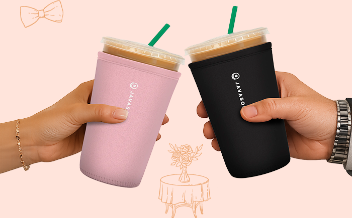 Two hands holding insulated tumblers in pink and black sleeves.
