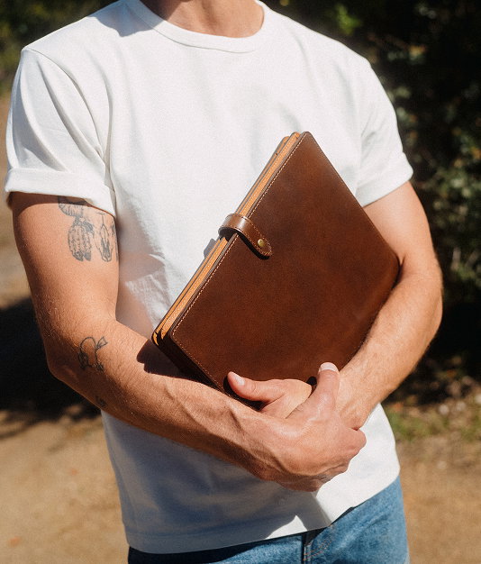 Man carrying a brown leather folio at his side