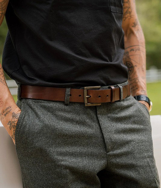 Brown leather belt with brass buckle worn with charcoal trousers