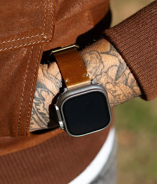 Brown leather Apple Watch band on a tattooed wrist