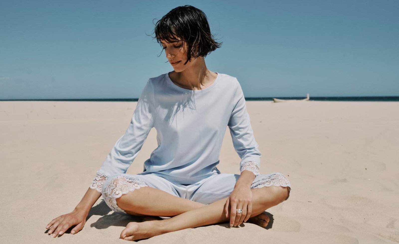 woman model sitting on beach wearing Blue Dove Moments pajama set