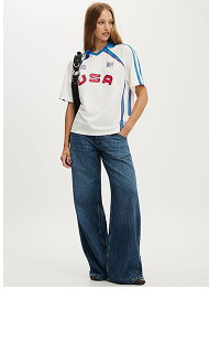 Model wearing white graphic tee and dark blue jeans