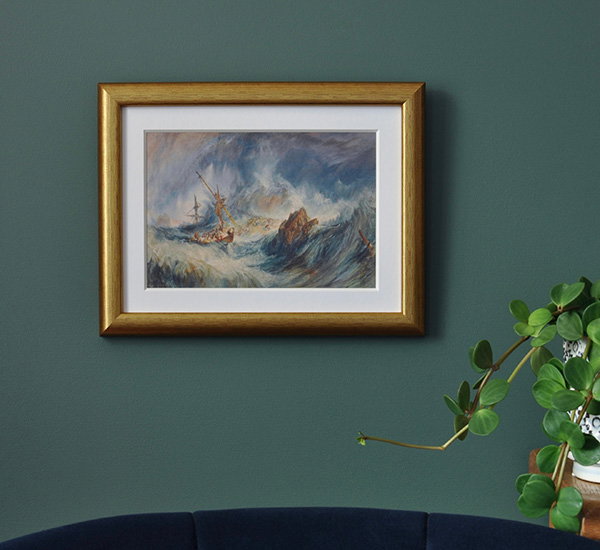 Gold framed print of J.M.W. Turner’s A Storm (Shipwreck) displayed on a green wall. - Shop Prints and Postcards.