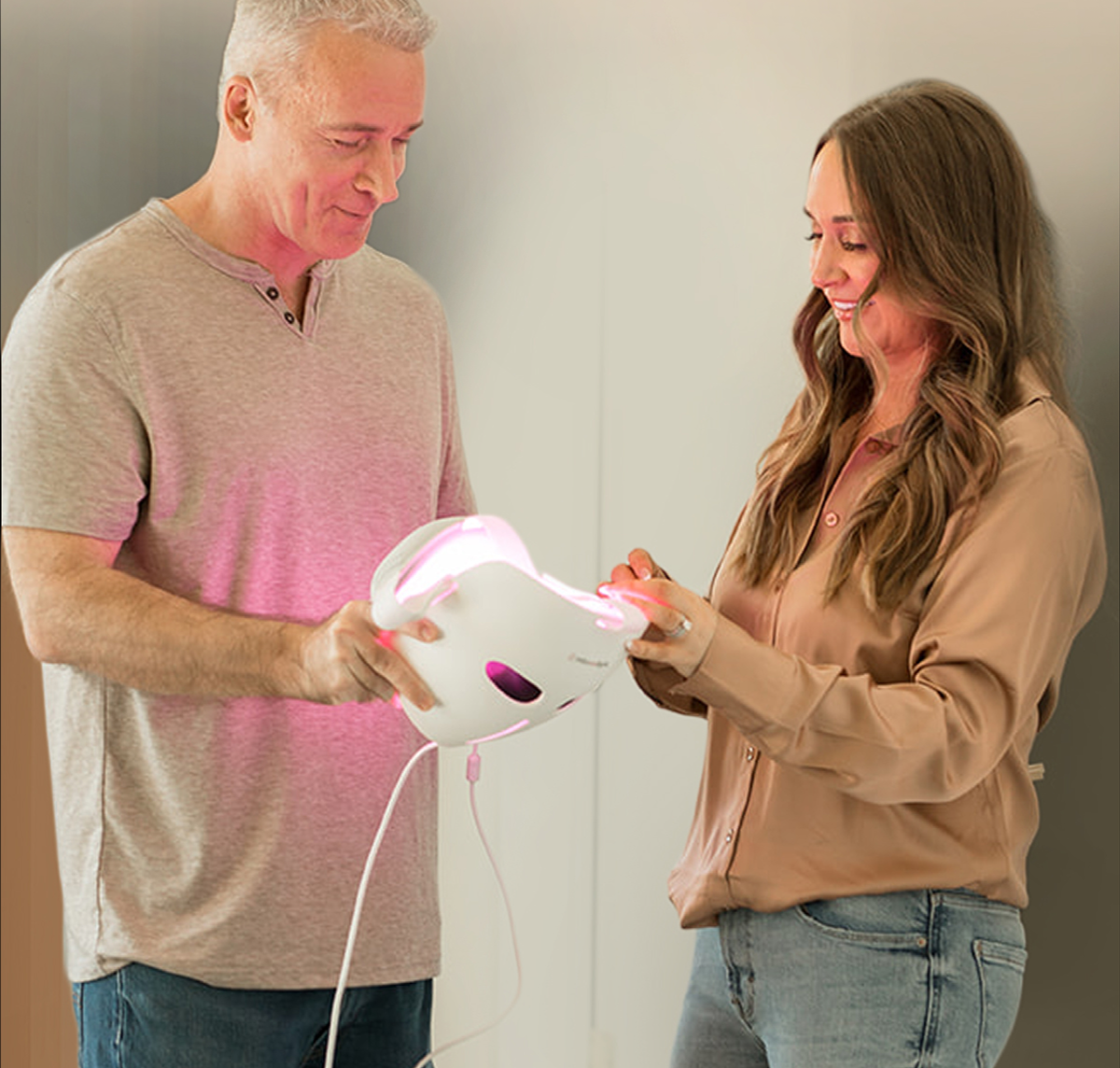 Man and woman look at red light therapy mask.