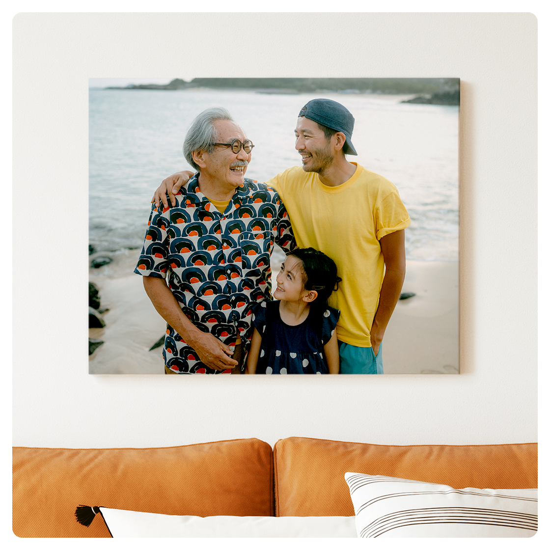 A 16x20 canvas hung above a couch shows three generations of a family enjoying time together at a lake.