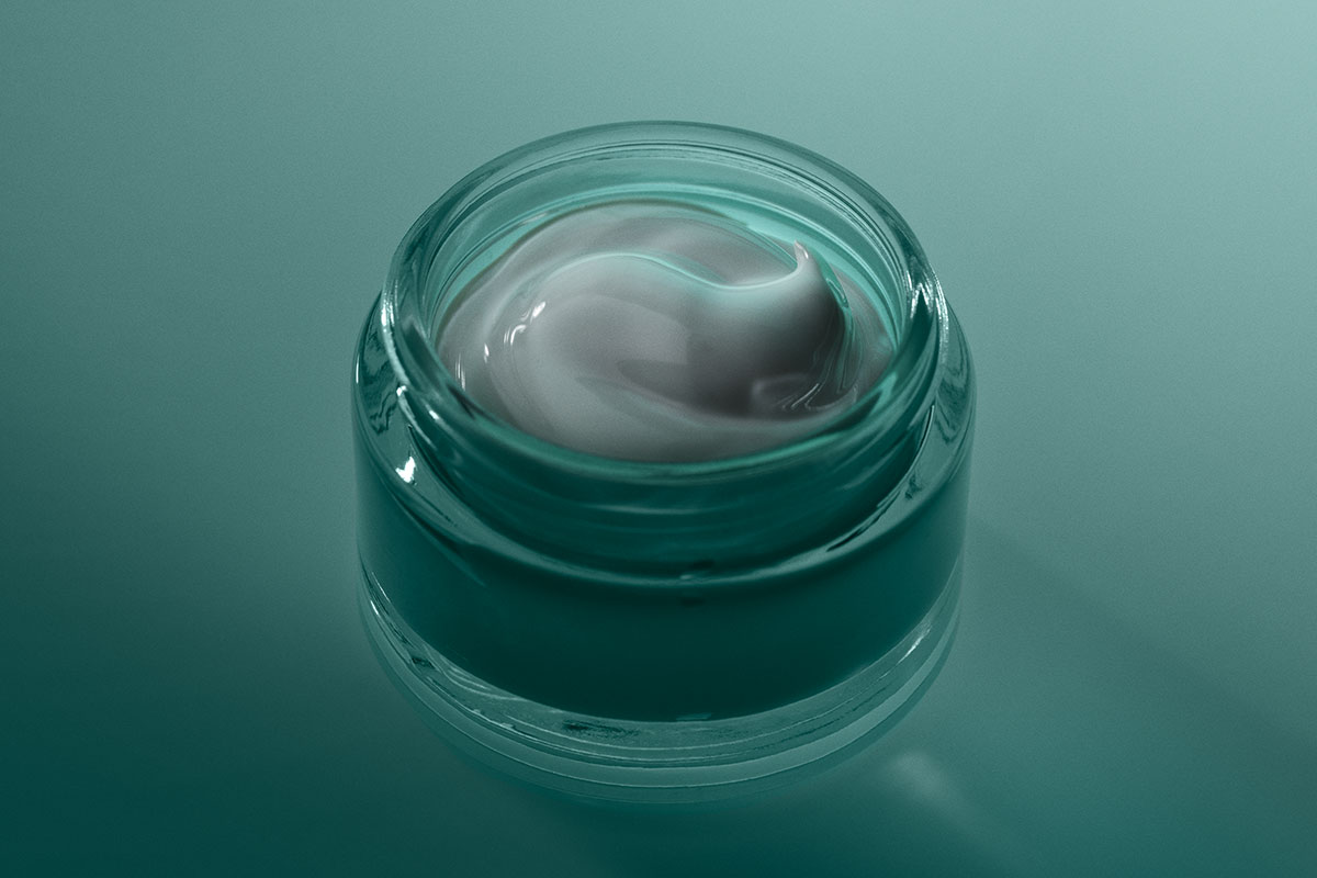 Eine durchsichtige Dose enthält eine graue Creme mit einer gewirbelten Textur, die eine luxuriöse Pflege verspricht.'