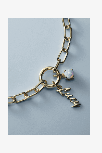 Yellow gold paperclip chain bracelet with script letter charm and opal gemstone accent.