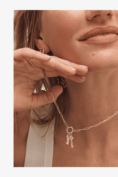 Close up of female model wearing gold script name necklace.