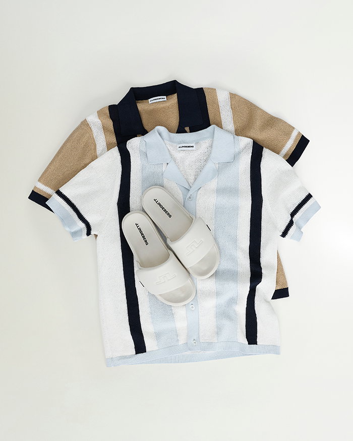flat lay image of two knit polos and pair of JL logo slides against a white background