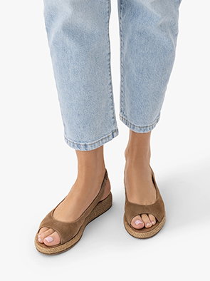 Woman wearing light blue jeans and brown open-toe wedge sandals.