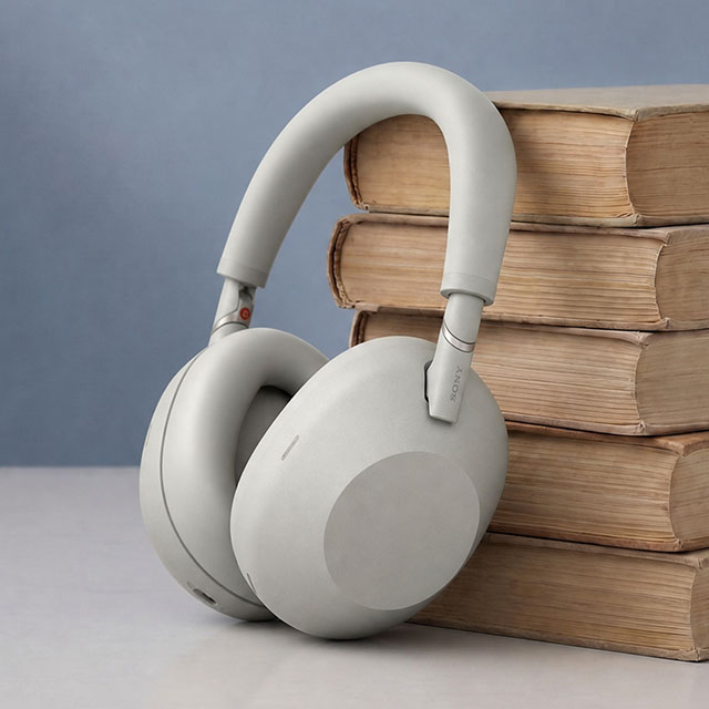 Grey headphones leaning against a stack of books.