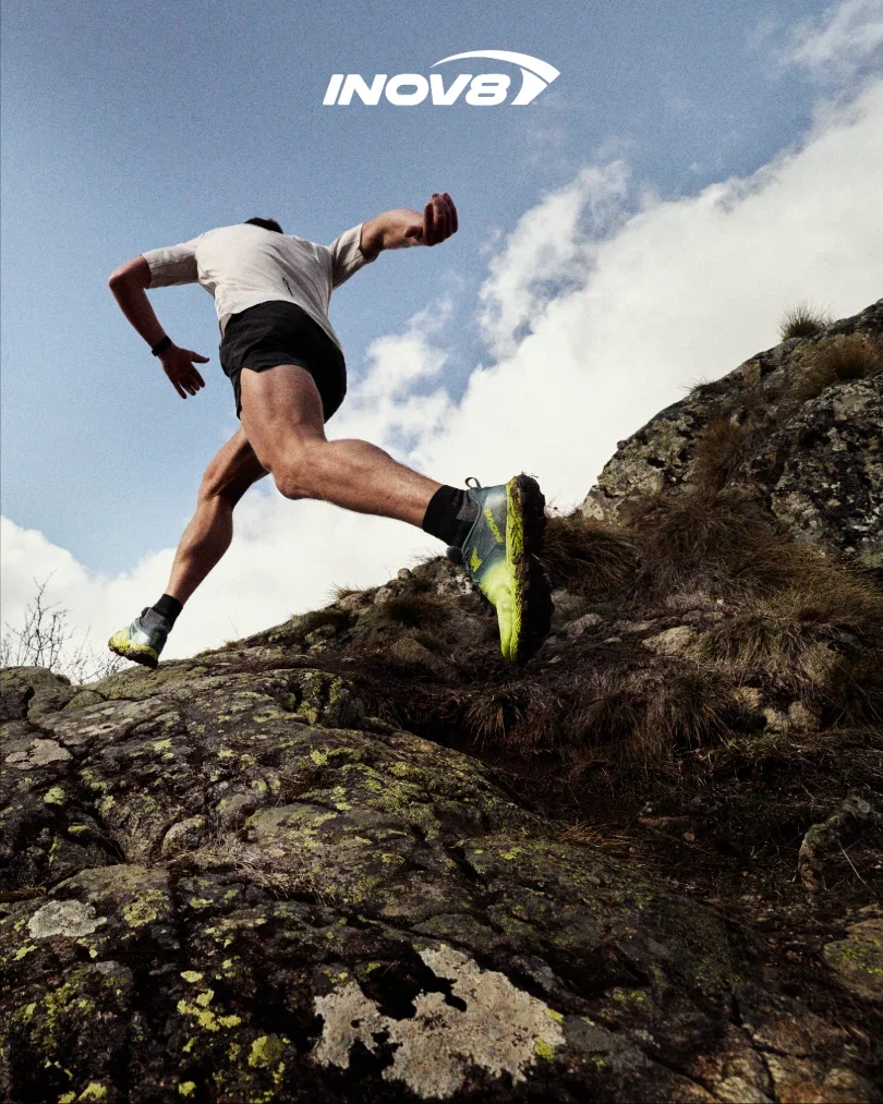A runner wearing bold red TRAILTALON ZEROs on a dark forest trail