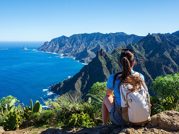 Wandererin blickt auf die Steilküsten Teneriffas