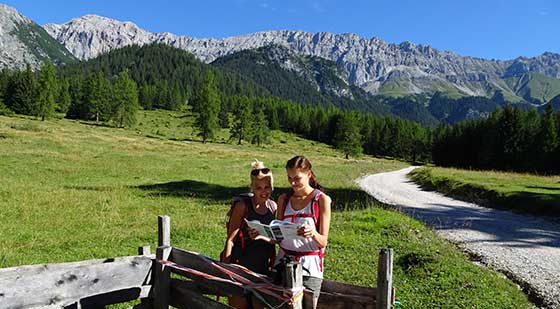 2 Frauen schauen auf einer Wanderung in den Bergen in die Karte