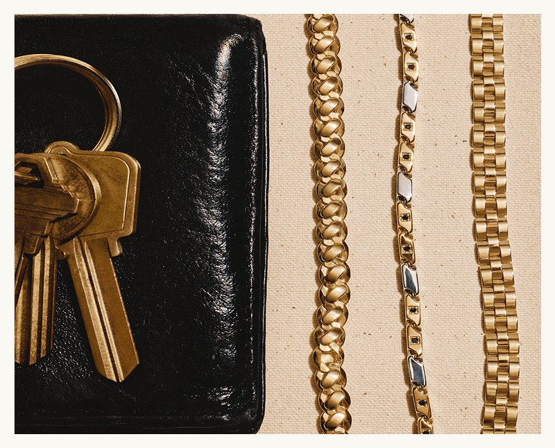 Black leather wallet with brass keys & three distinct styles of gold-toned necklace chains.