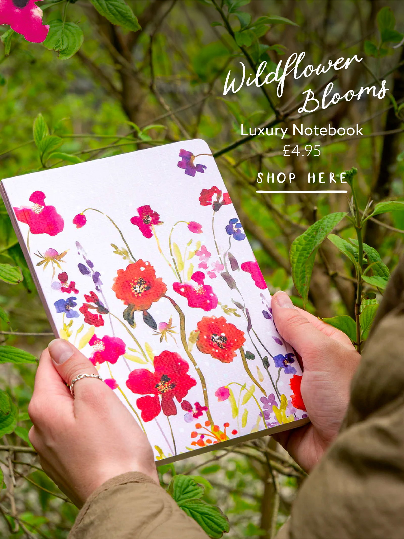 Wildflower Whispers notebook held outdoors among leafy greenery, showcasing the collection's vibrant floral artwork.