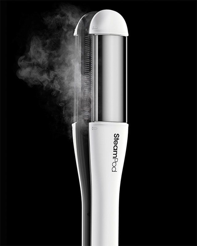 A white SteamPod steam hair straightener emits vapor against a black background.