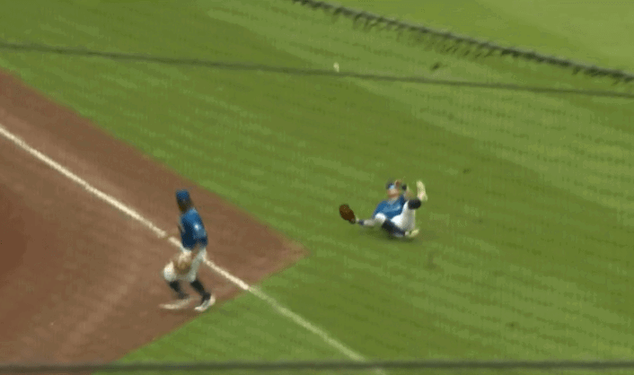 A ball is deflected by a left fielder as the third baseman looks on