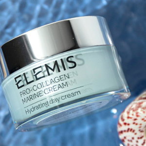 ELEMIS jar laying in water next to a speckled seashell