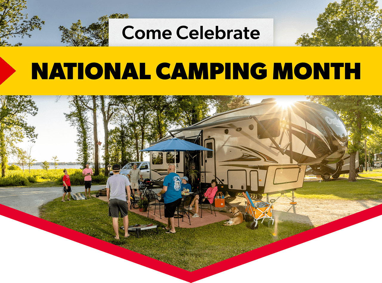 A family enjoys their campsite next to their RV. A headline reads: Come celebrate National Camping Month.