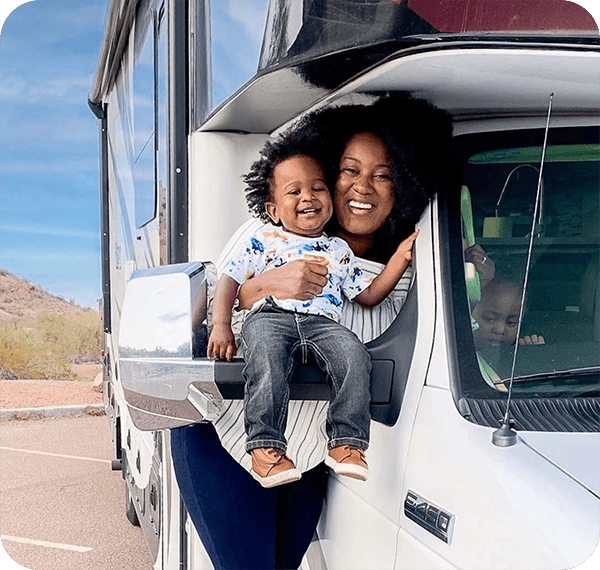 A mother holds her baby in the window of their RV.
