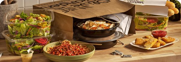 Olive Garden To Go meals including pasta, salad, breadsticks, and appetizers alongside a takeout bag.