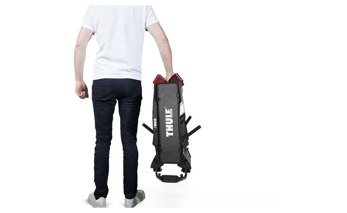 Eine Person, die den zusammengeklappten Träger in der Hand hält