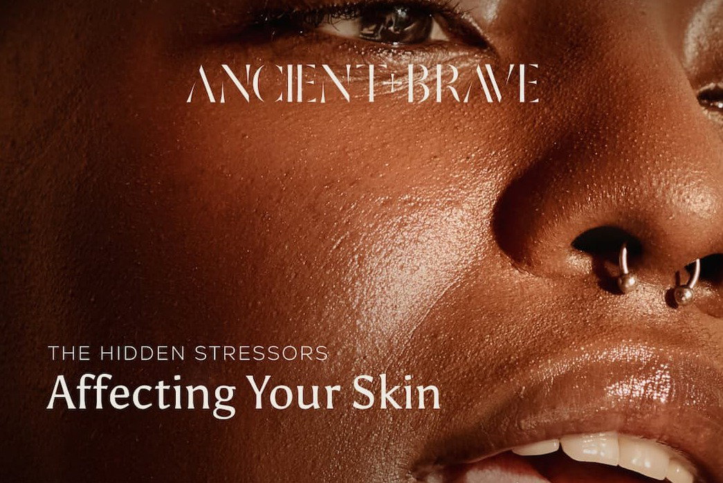 Ancient + Brave: A close-up portrait of radiant, glowing skin. Text overlay reads: The Hidden Stressors Affecting Your Skin