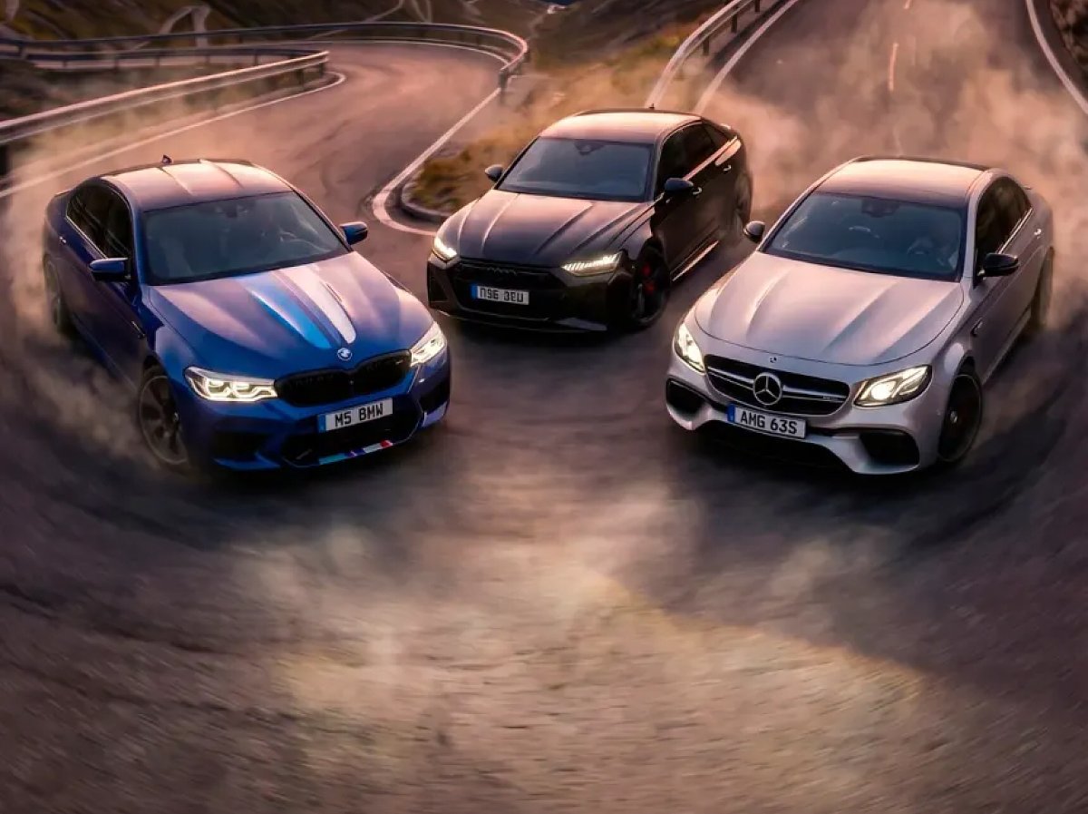 Three luxury cars drifting on a winding road with smoke and dust.