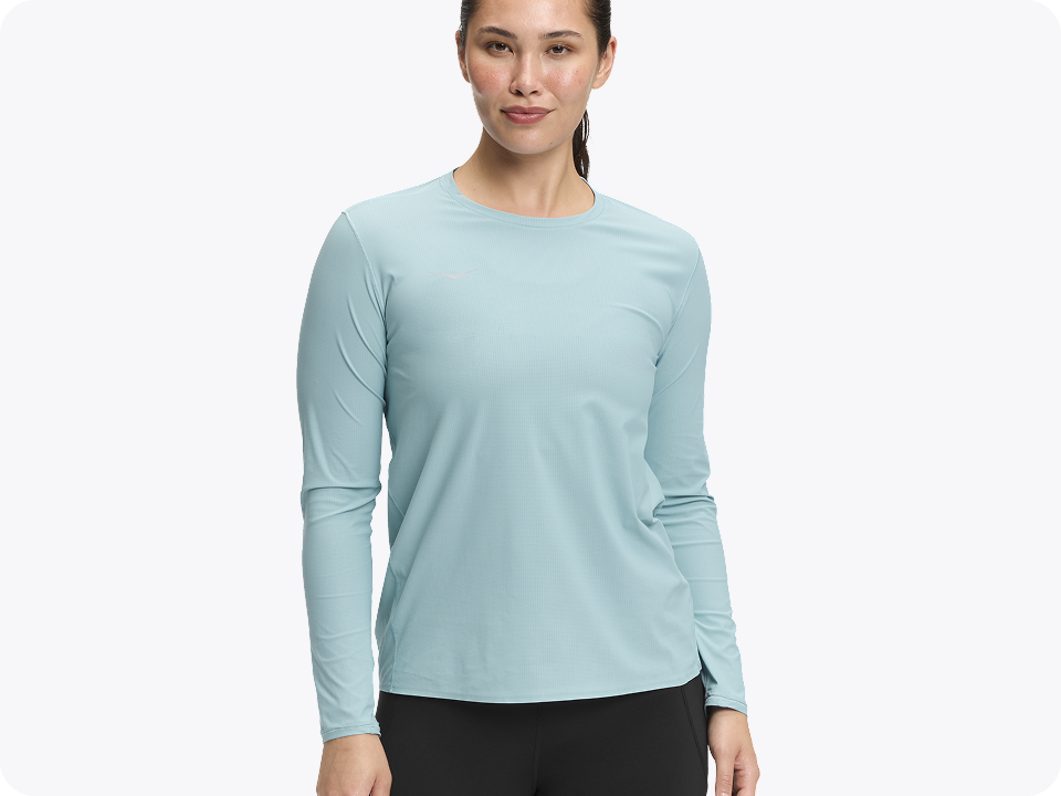 Model in light blue textured long-sleeve shirt and black pants on white background.