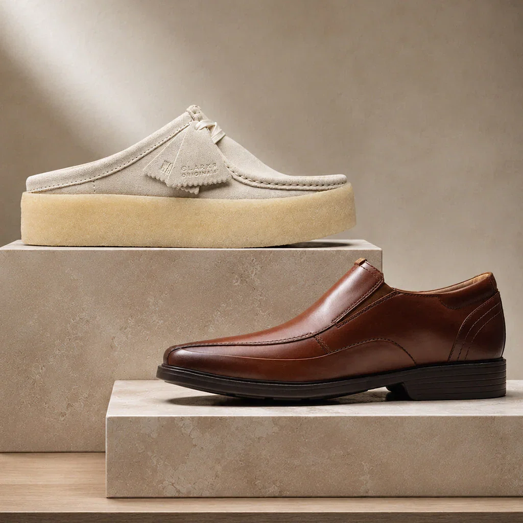 Best-Selling Clarks footwear collection featuring a cream suede mule and brown leather loafer displayed on stone platforms.