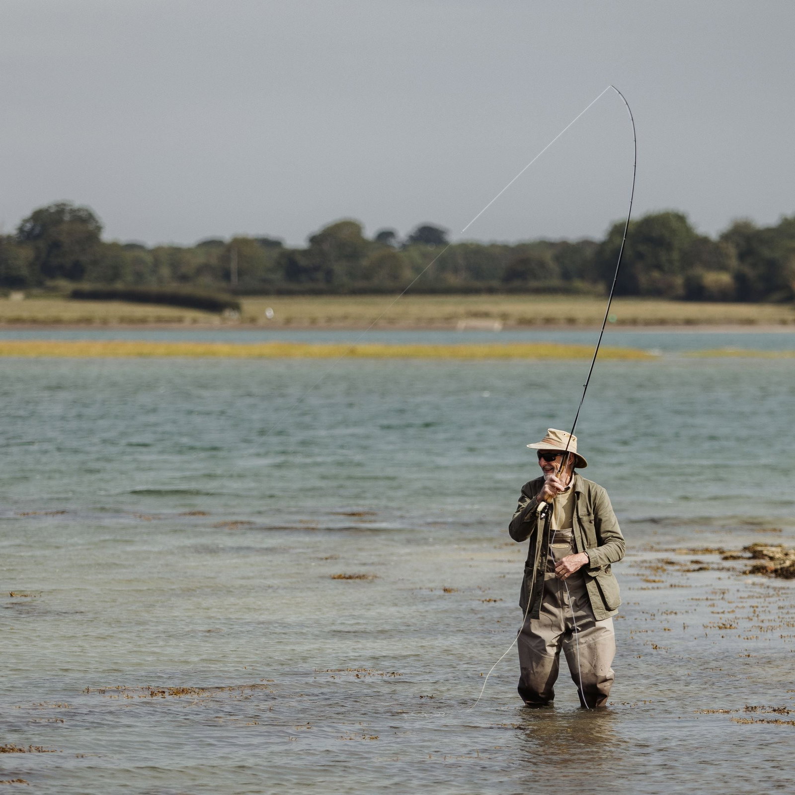 A man fishing in knee-deep water on the English coast