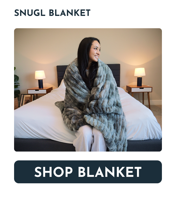 Cozy woman wrapped in a soft blanket sitting on a bed with lamps.