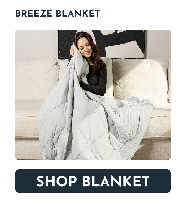 A woman sitting on a couch, holding a light gray blanket.